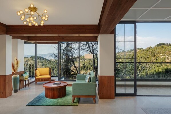 A modern interior with a wooden ceiling, large windows, and a view of a mountainous landscape. - Justa Luxe Hollow Oak Mussoorie (Dehradun)
