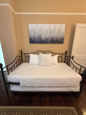 A bed with a white mattress and pillows, a headboard, and a wall-mounted painting. - Historic House Near Downtown and the Riverwalk (San Antonio)