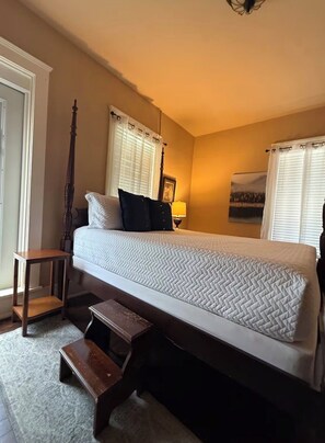 A bedroom with a large bed, a wooden bench, a nightstand, and a picture on the wall. - Historic House Near Downtown and the Riverwalk (San Antonio)