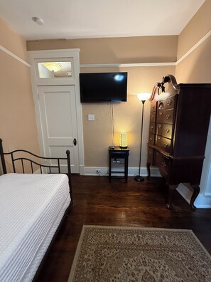 A bedroom with a bed, a dresser, a television, a lamp, and a rug. - Historic House Near Downtown and the Riverwalk (San Antonio)