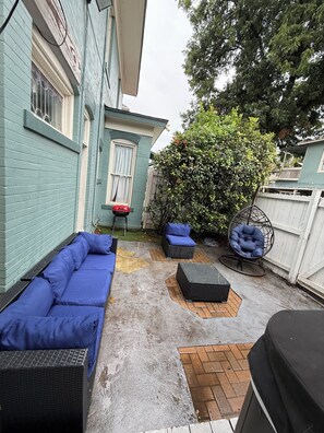 A patio with a blue sofa, a wicker chair, and a small table. - Historic House Near Downtown and the Riverwalk (San Antonio)