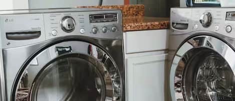 A laundry area with two front-loading washing machines and a cabinet above.