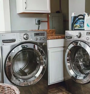 A laundry area with two front-loading washing machines and a cabinet above. - Historic House Near Downtown and the Riverwalk (San Antonio)