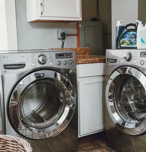 A laundry area with two front-loading washing machines and a cabinet above. - Historic House Near Downtown and the Riverwalk (San Antonio)