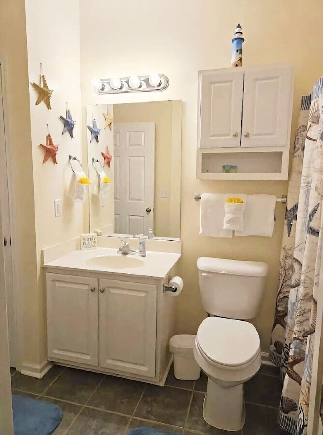 A bathroom with a sink, mirror, toilet, and cabinets.