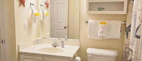 A bathroom with a sink, mirror, toilet, and cabinets.
