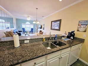 A kitchen with granite countertops, stainless steel sink, and white cabinets.