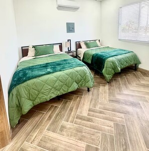 A room with two beds, a light switch, and a window with blinds. - Green Spot Rest & Relax in Puerto Peñasco. 2BR/2BA (Puerto Peñasco)