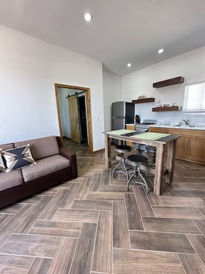 A modern kitchen with a dining area, a sofa, and a herringbone-patterned floor. - Green Spot Rest & Relax in Puerto Peñasco. 2BR/2BA (Puerto Peñasco)