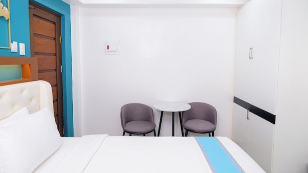 A hotel room with a bed, a small table, two chairs, and a wardrobe. - Le Dream Hotel (Vigan)