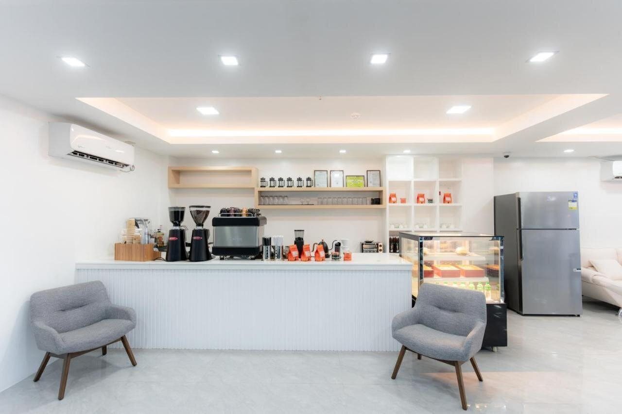 A modern kitchen area with a central island, coffee machines, and a refrigerator.