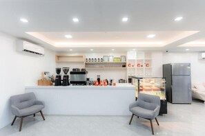 A modern kitchen area with a central island, coffee machines, and a refrigerator.