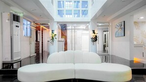 A modern interior with a central white sofa, glass partitions, and a high ceiling with natural light. - Le Dream Hotel (Vigan)