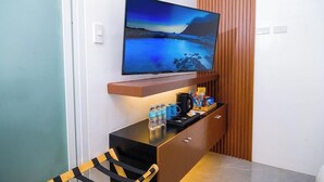 A modern room with a flat-screen TV mounted on the wall, a wooden cabinet below, and a small seating area with a chair. - Le Dream Hotel (Vigan)