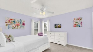 A bedroom with a bed, a dresser, a ceiling fan, and floral artwork on the walls. - 6 bedroom 6 Bath Palm Paradise close to Orlando Theme Parks (Kissimmee)