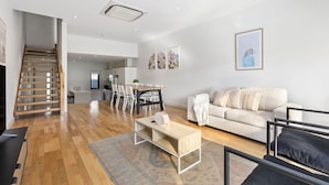 A modern living space with a staircase, a dining area, and a sofa. - Domi Rentals The Chadstone Homes (Chadstone)
