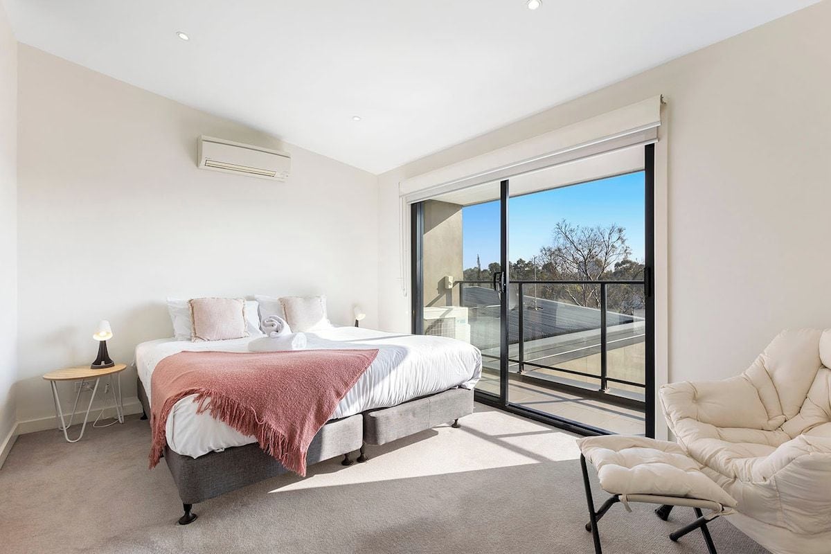A bedroom with a bed, bedside table, lamp, and a chair.