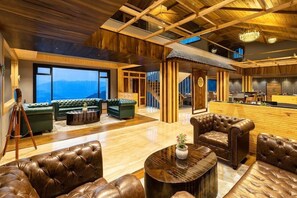 A spacious lobby with leather sofas, a wooden reception desk, and a staircase leading to upper floors. - Justa Luxe Cliffend Resort and Spa Mashobra (Shimla)