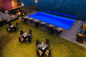 A poolside area with a rectangular pool, outdoor seating, and a staircase leading to an upper level. - Justa Luxe Cliffend Resort and Spa Mashobra (Shimla)