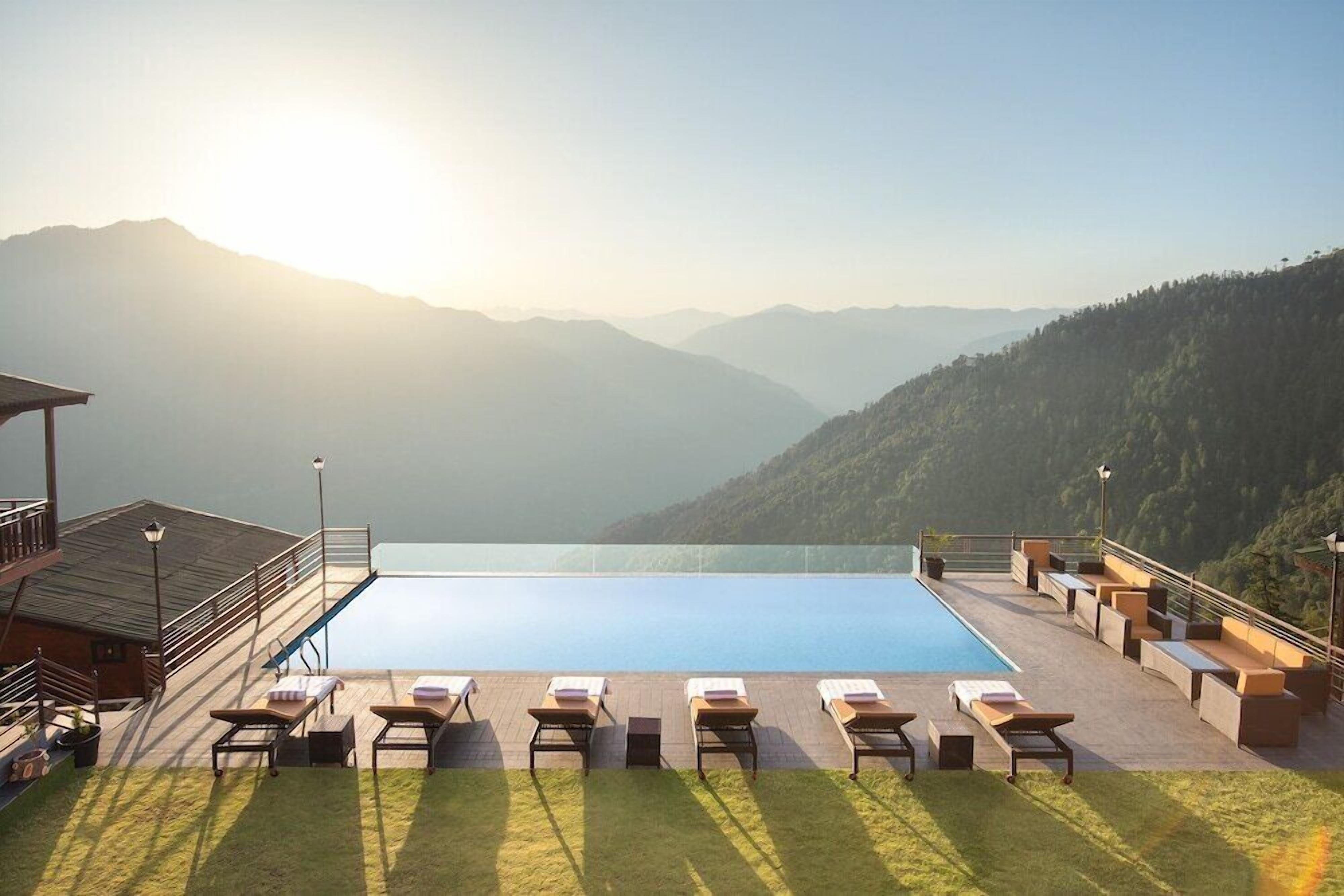 Area piscina con poltronne da relax e vista sulle montagne.