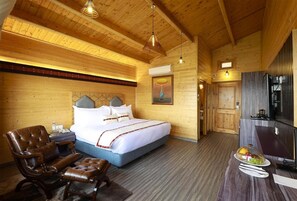 Un interior de madera con una cama, un sillón de cuero, una mesa de comedor con fruta y un televisor.