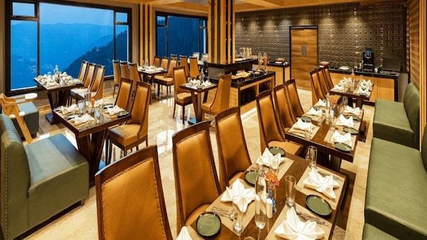 A restaurant with multiple dining tables, chairs, and a bar area. - Justa Luxe Cliffend Resort and Spa Mashobra (Shimla)
