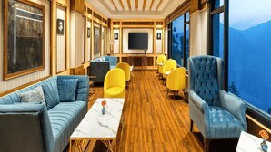 A room with a wooden floor, a sofa, a chair, a table, and a television. - Justa Luxe Cliffend Resort and Spa Mashobra (Shimla)