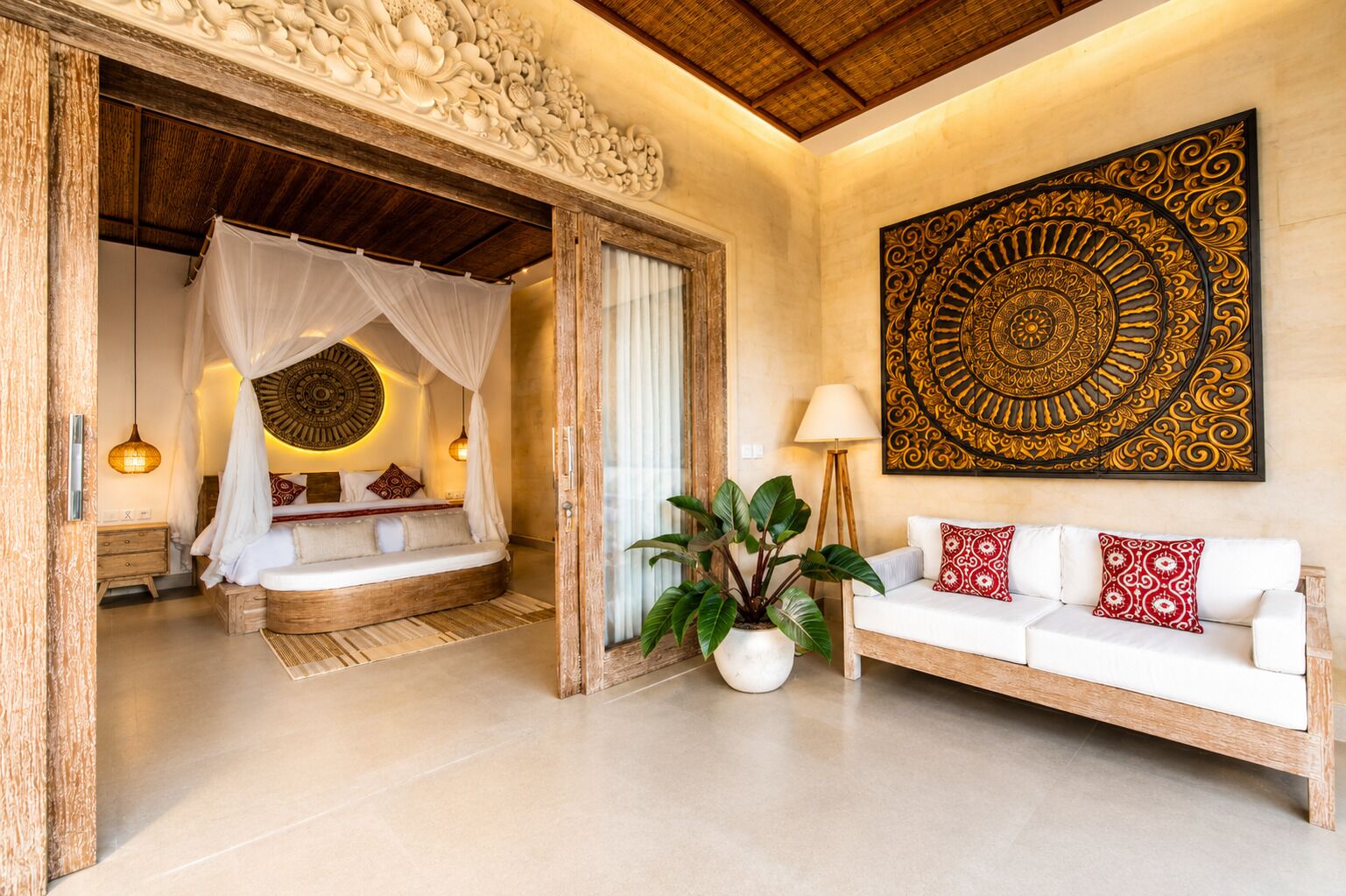 Une chambre à coucher avec un lit à baldaquin, un coin salon avec un canapé et un grand élément décoratif mural.