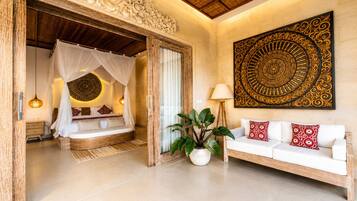 Une chambre à coucher avec un lit à baldaquin, un coin salon avec un canapé et un grand élément décoratif mural.