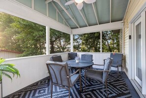 Eine überdachte Terrasse mit einem runden Tisch und Stühlen, umgeben von einem gemusterten Teppich.
