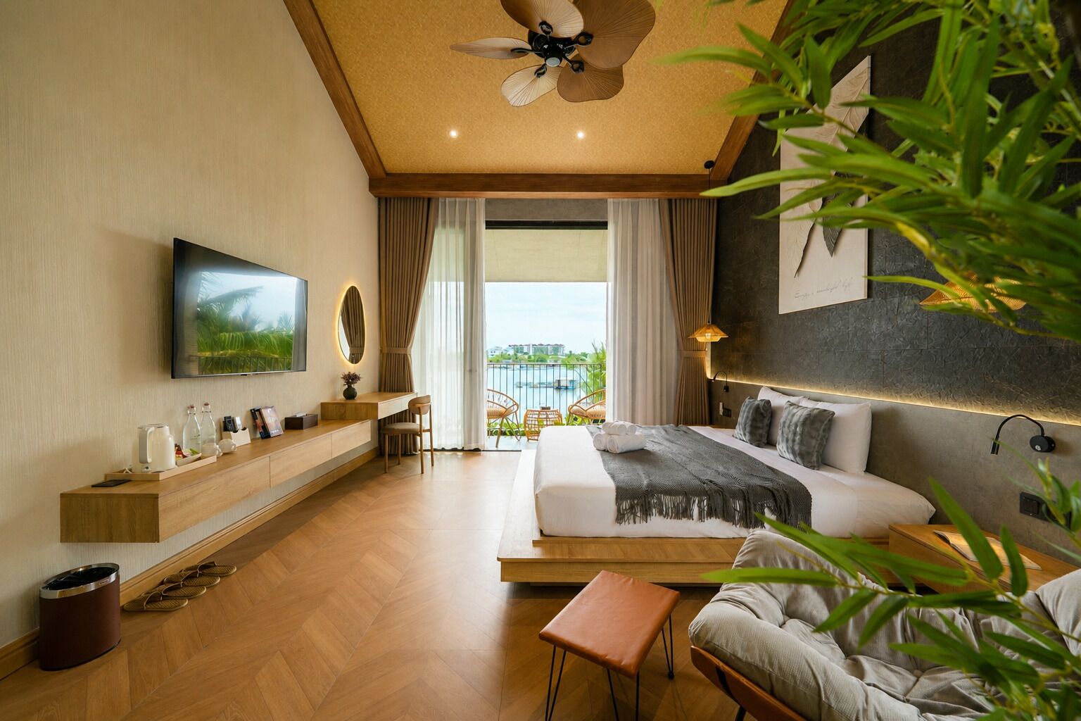Ett modernt hotellrum med en stor säng, ett skrivbord, en tv och en balkong med utsikt.