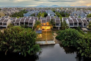 Un resort con varias construcciones tipo bungalow, un área de piscina central y follaje circundante.