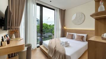 Quarto de hotel moderno com uma cama grande, uma escrivaninha com computador, vista para o exterior e um objeto decorativo redondo na parede.
