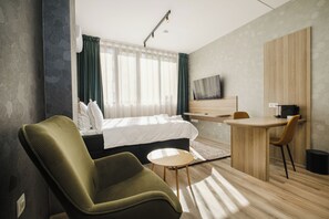 Una habitación de hotel moderna con una cama, un escritorio, una silla y un televisor.