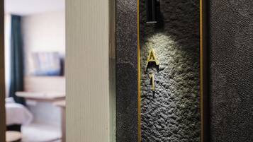 Un mur à texture, avec une poignée de porte dorée et un objet noir posé dessus.