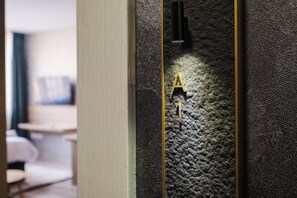 A textured wall with a gold door handle and a black object on it.