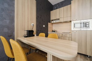 A modern kitchen with a wooden table and chairs, a built-in oven, and a coffee machine. - A17 Suites (Plovdiv)