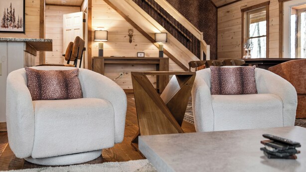 Un interior acogedor con dos sillones cómodos, una escalera de madera y un comedor.