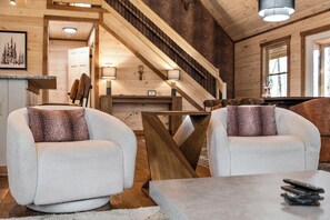 Ein gemütliches Interieur mit zwei bequemen Sessel, einer Holztreppe und einem Essbereich.