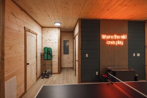 Ett rum med träpanel, ett bord för bordtennis, en neonreklamskylt och en dörr.