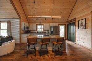 Ein Holzblockhaus-Interieur mit Küche, Barhocker und einer Sitzecke.