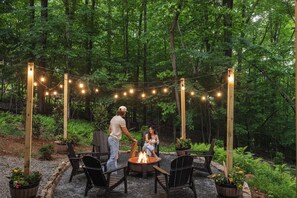 An outdoor seating area with chairs and a fire pit, surrounded by trees and string lights. - New listing discount! Pickleball- Hot Tub- Gameroom- 6 min to town: all 5-stars! (Blue Ridge)
