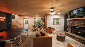 Un espacio interior acogedor con mesa de ping pong, sofá de cuero y chimenea.