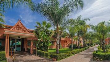 A resort with palm trees, a tiled roof, and a paved walkway.