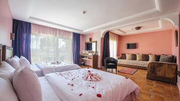 Une chambre d’hôtel avec deux lits, un canapé, une télévision et un bureau.