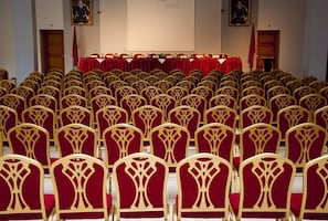 Rows of chairs with a red table and a podium in a conference room.