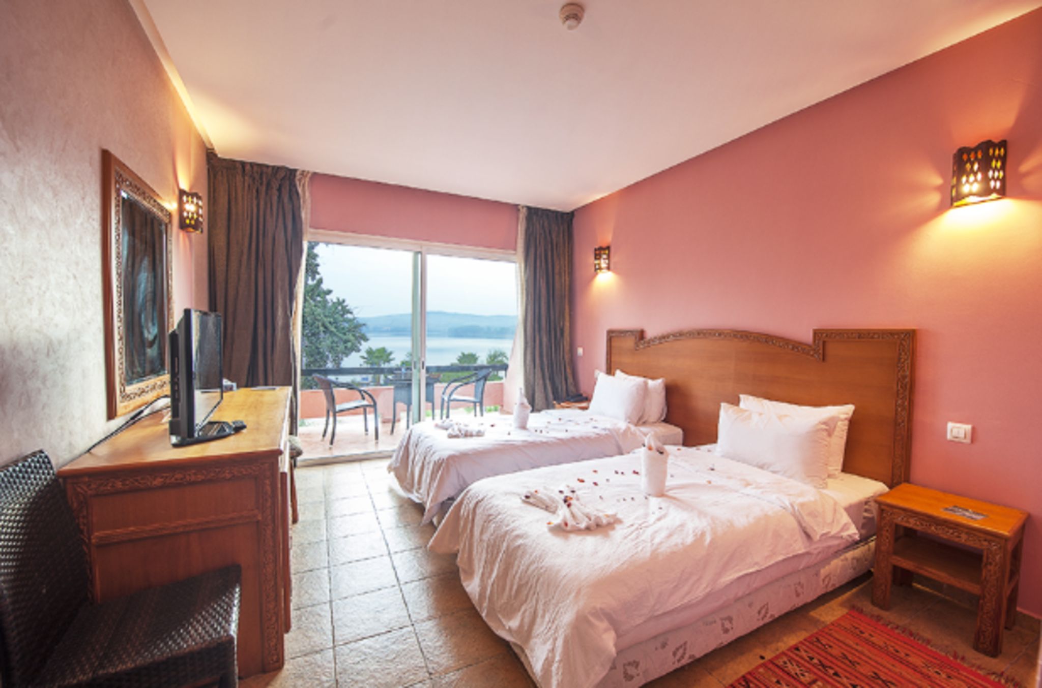 Une chambre d’hôtel avec deux lits, un bureau, une chaise et une vue sur l’extérieur.
