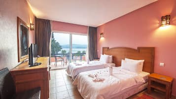Une chambre d’hôtel avec deux lits, un bureau, une chaise et une vue sur l’extérieur.