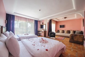 A hotel room with two beds, a sofa, a TV, and a desk. - Dar Eddaya Hôtel (Oulmes)