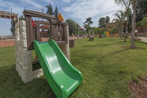 A playground with a green slide, a climbing structure, and a fenced area. - Dar Eddaya Hôtel (Oulmes)